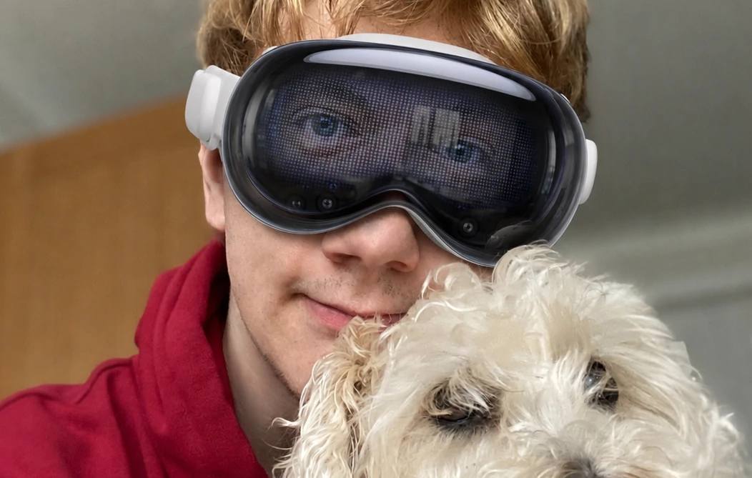 Niall Horn wearing an Apple Vision Pro, its EyeSight display showing his eyes, with his dog Lucy beside him